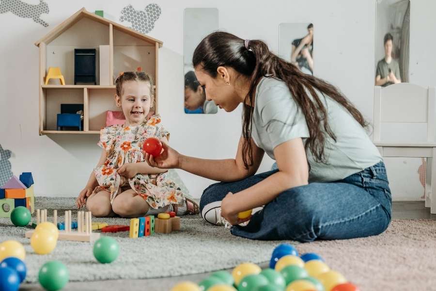 Une éducatrice joue avec une enfant dans une structure adaptée comme mode de garde.
