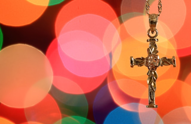 Croix en or sculptée sur une chaîne, une idée élégante de cadeau de baptême sur fond lumineux flouté.