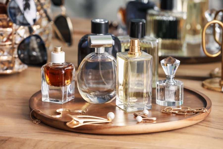 Collection de flacons de parfum et bijoux sur un plateau en bois clair