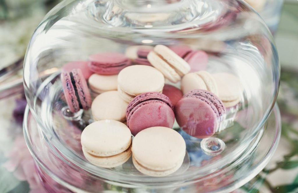 Cloche en verre garnie de macarons roses et beiges pour des idées déco et friandises candy bar mariage